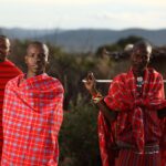 Three African men wrapped in traditional red Maasai blankets
