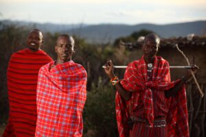 Three African men wrapped in traditional red Maasai blankets