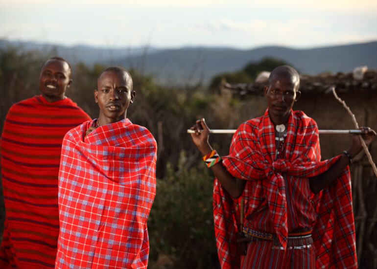 Three African men wrapped in traditional red Maasai blankets